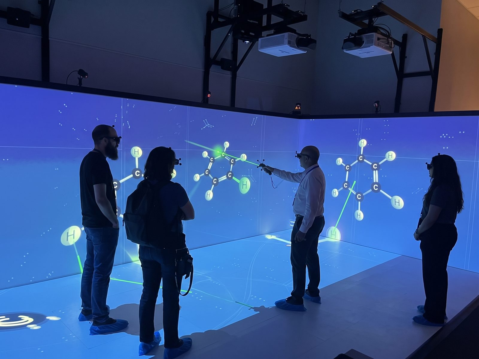 Visitors in 3D glasses explore a molecule projected on the CAVE walls